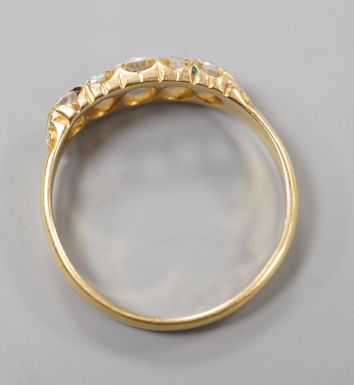 A late Victorian 18ct gold and graduated claw set five stone diamond half hoop ring, size N, gross weight 2.5 grams.